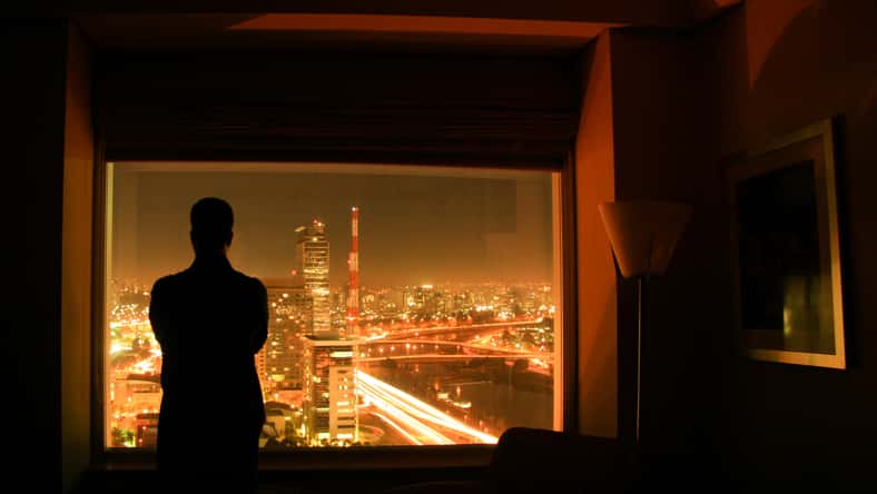 Silhouete of a person against the night landscape of the city of Sao Paulo, in a hotel room, in Brazil