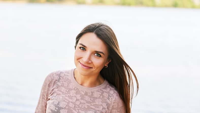 Outdoor portrait of young beautiful woman relaxing by river on a nice warm day
