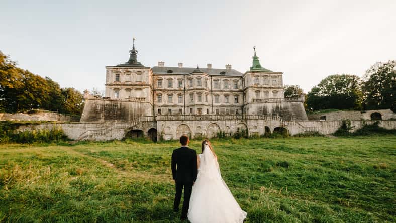 Newlyweds are walking their backs to the vintage Castle, renaissance palace for the wedding ceremony. Photo shoot near Medieval Castle.