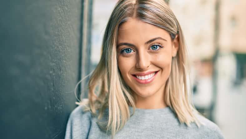 Young blonde girl smiling happy standing at the city.
