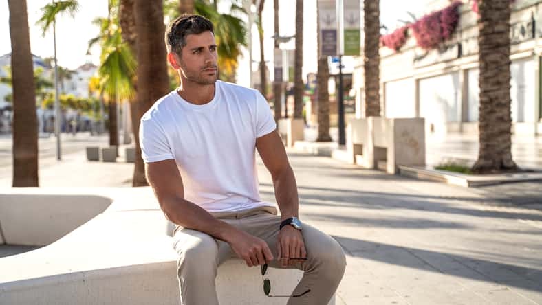 Handsome young man wearing white tshirt posing on city street background. Casual style. Fashionable guy. Summer vibes.
