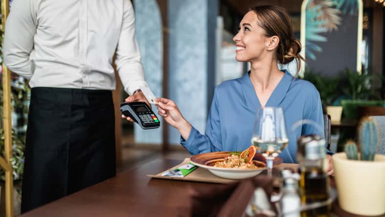 Beautiful young woman paying for her order with a credit card in a restaurant.