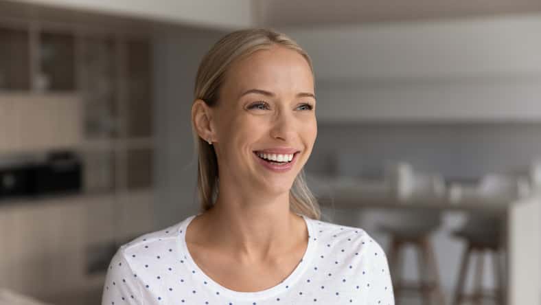 Happy beautiful 30s blonde woman home head shot portrait. Cheerful positive female homeowner in casual enjoying being in new apartment, looking away with toothy smile, laughing, thinking of future,