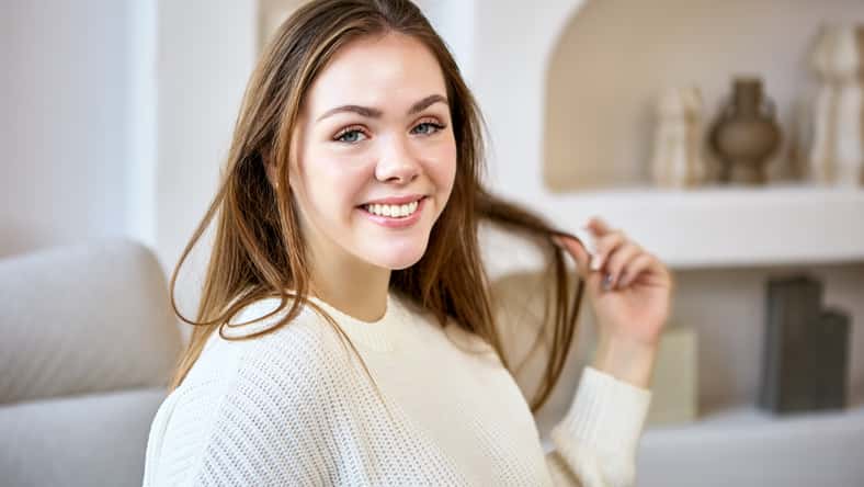 Portrait of smiling european young woman on sofa in living room.
