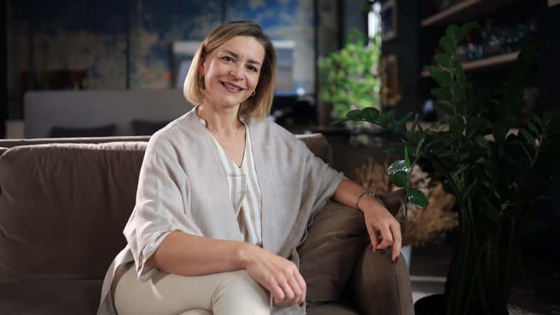Beautiful blond middle aged woman relaxing sitting on sofa.