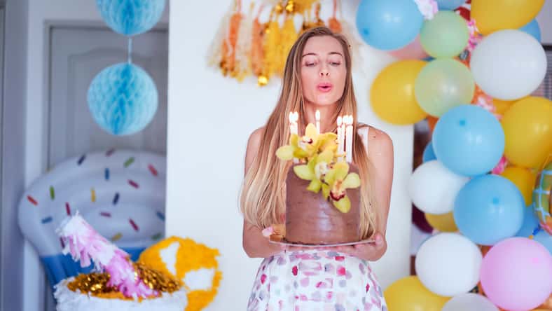 Party and celebration. Happy young woman with bithday cake at home.