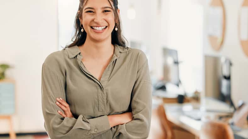 Shot of an attractive young businesswoman standing alone in the office with her arms folded.