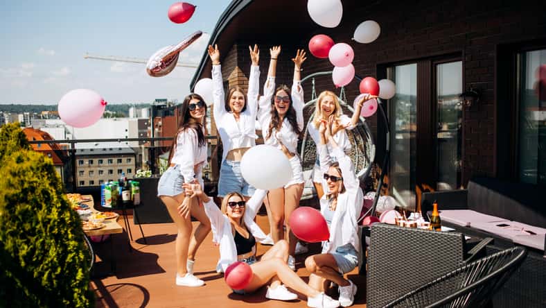 Happy and cheerful group of women friends together dancing and having fun on the rooftop at home. Bachelorette party.