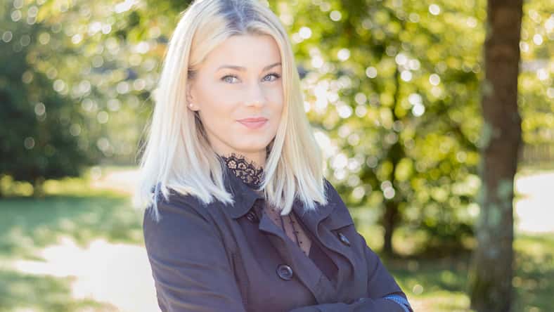 pretty smiling blonde woman looking at camera in a park