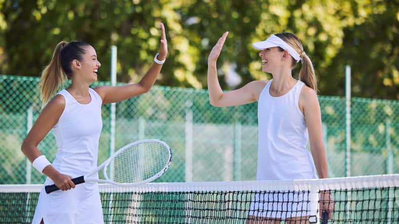 Tennis match winner and fit female athlete high five hands to success, celebrating after game on outdoor sports court. Women training exercise for wellness, healthy fitness lifestyle and summer fun