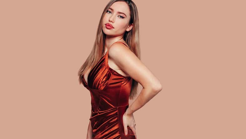 Portrait of young stunning model with bright impressive red lips. Studio photo shoot of pretty woman in fashionable red dress. Modern fashion and youth concept.