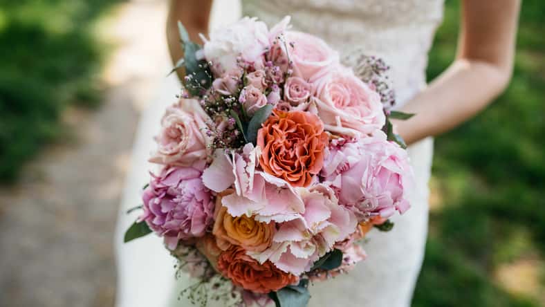 a bride holding a bouquet of flowers in her hands and a wedding gown