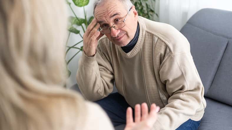Mature man at a session with a psychologist. The doctor listens and writes. Help with depression, psychiatric diagnosis