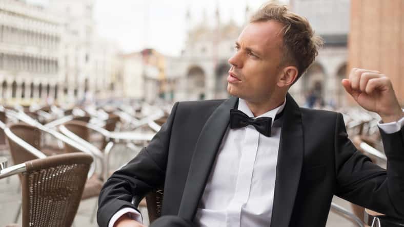 Stylish young man sitting in cafe in tuxedo
