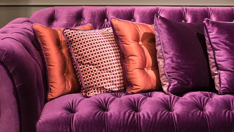 Close up of violet velvet sofa and cushions with vintage style.