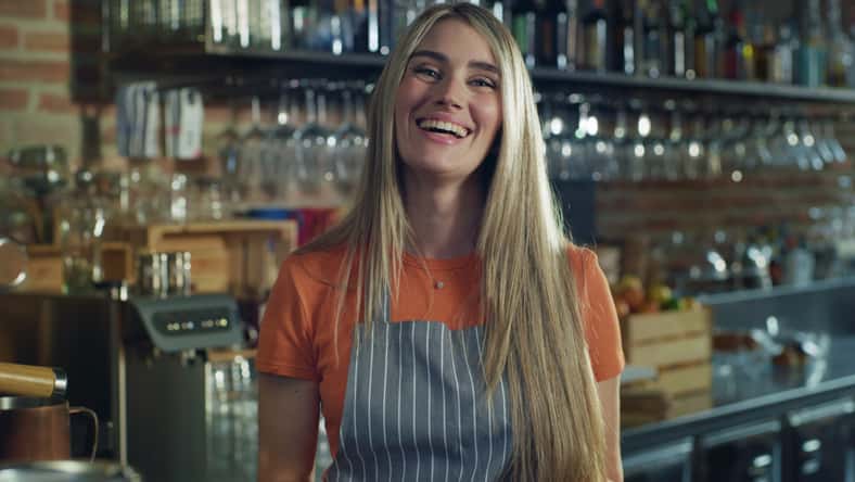 portrait of young friendly female bartender working at a bar during day time