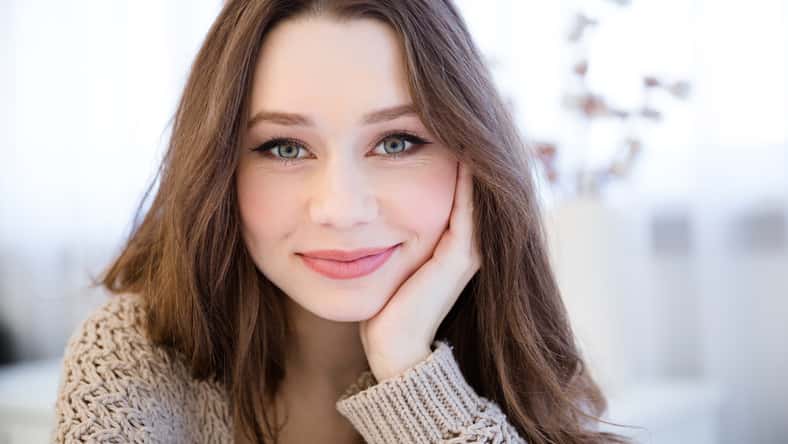 Portrait of beautiful happy young woman with long hair in the room