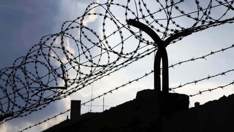 Dramatic clouds behind barbed wire fence on a prison wall