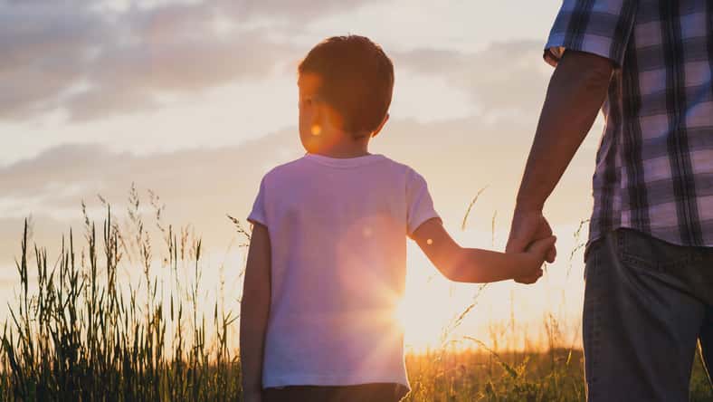 Father and son playing at the park at the sunset time. Concept of friendly family.