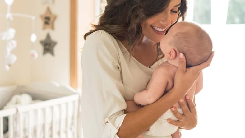 Young mother holding her baby in the bedroom