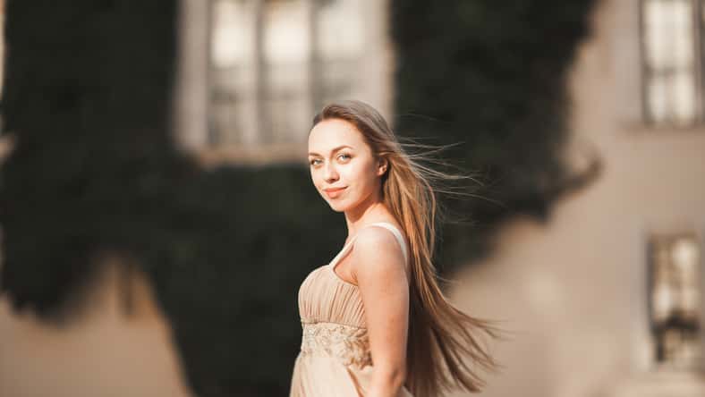 Beautiful girl with long hair posing in old castle with columns. Krakow Vavel.