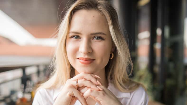Portrait of beautiful young blonde woman drinking a cup of tea in balcony cafeteria. Happy smiling female relaxing in a coffee shop
