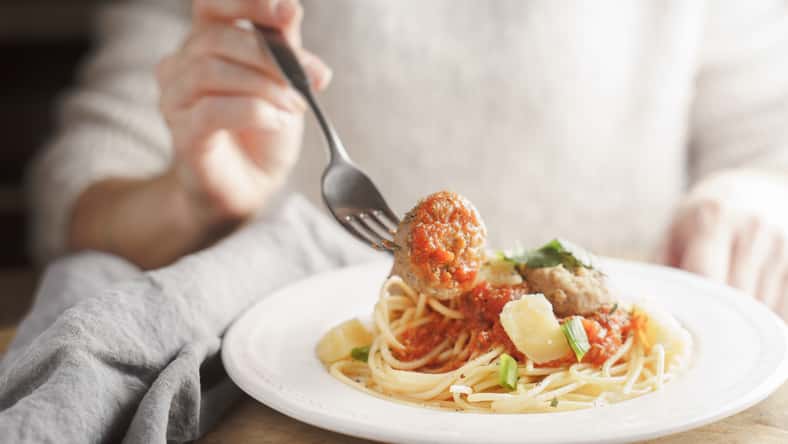 Woman eating spaghetti with meatballs