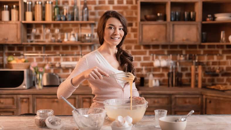 portrait of smiling woman mixing ingredients for cake
