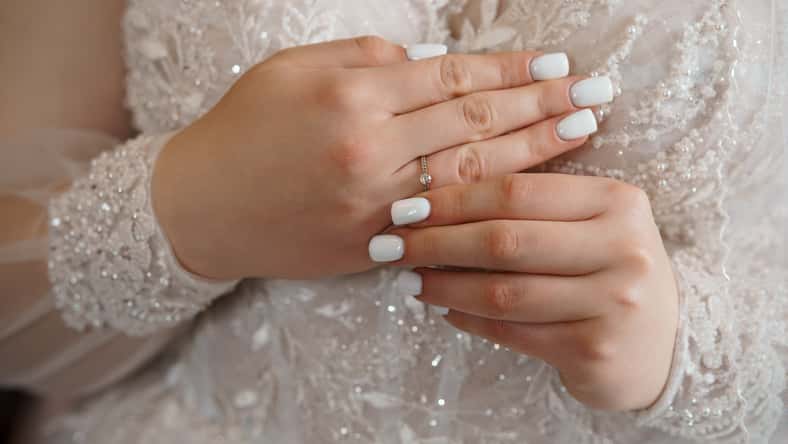 Close-up shot of a bride's hands displaying a delicate diamond engagement ring, symbolizing love, commitment and a joyous wedding moment