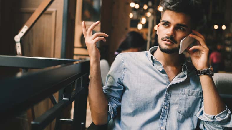 Portrait of young handsome man in blue shirt talking on phone