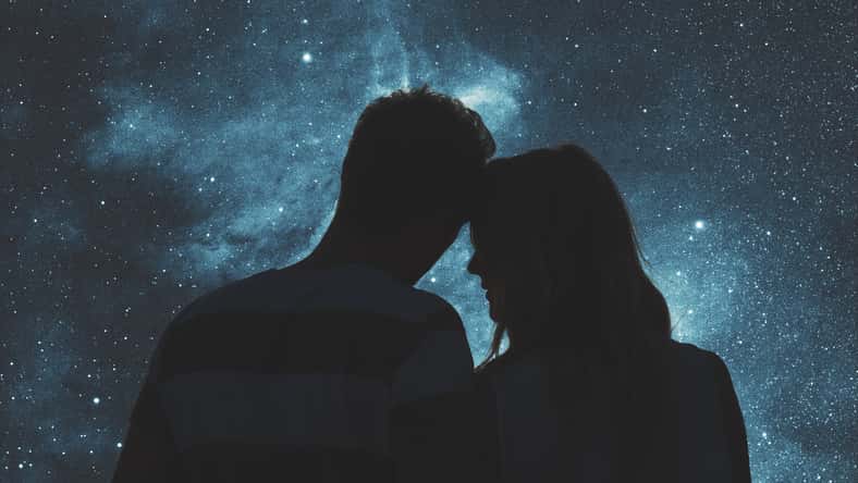 Silhouettes of a young couple under the starry sky.