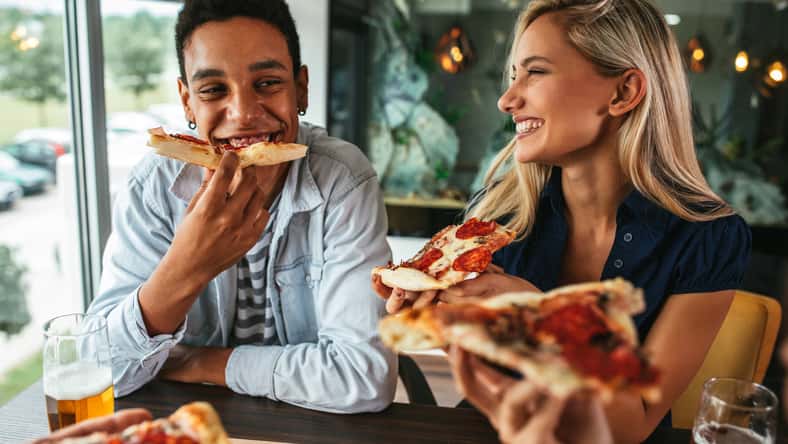 Shot of a young happy couple eating pizza in a restaurant