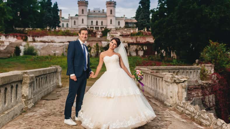 The bride and groom walking along the old bridge. At background the old castle