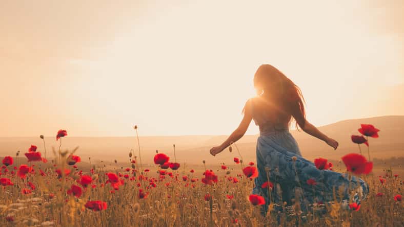 Young beautiful woman in spring field. concept of freedom. walking in amazing poppy field. Warm sunset colors. Soft colors.
