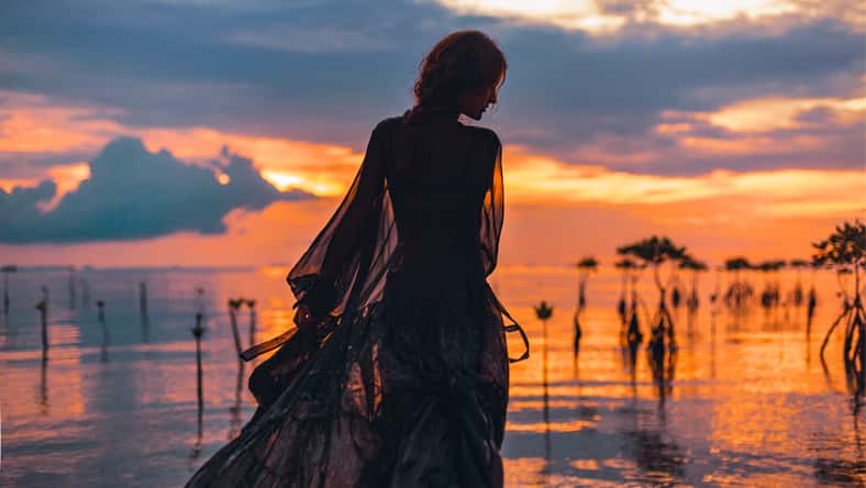 young woman standing in water at sunset silhouette
