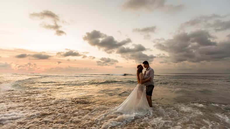 Bride and groom hugging on the beach standing in the sea water