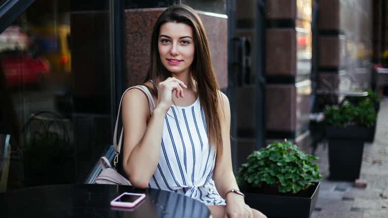 Young pretty woman blogger in cafe with smartphone