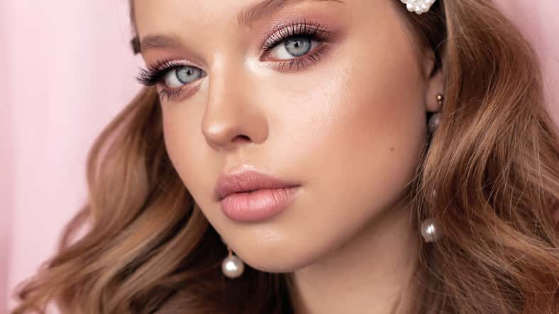fashion photo of beautiful young woman with dark natural hair and tender makeup with pearl accessories