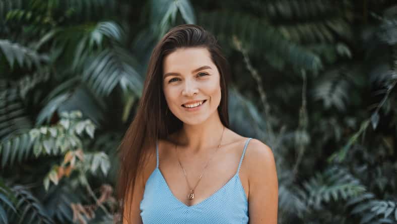 Portrait of young and beautiful woman with perfect smooth skin in tropical leaves.