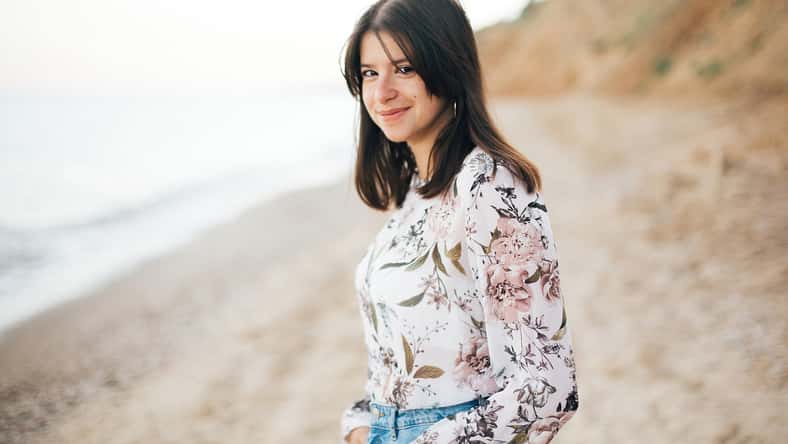 Elegante chica hipster que camina por la playa en el mar. Retrato tranquilo de una feliz mujer boho de moda relajándose en Sandy Cliff en Tropical Island. Viajes y vacaciones de verano. Espacio para el texto