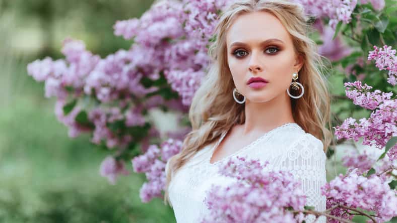 Beautiful woman enjoying lilac garden, young woman with flowers in green park. cheerful teenager walking outdoor. soft light style color.