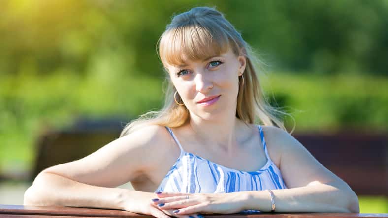 Portrait of a woman of Caucasian nationality on a summer sunny day in the park against the backdrop of greenery.