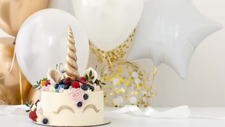 Close up of little girl's birthday party table with unicorn cake