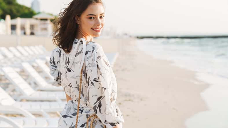 Back view image of a pleased happy young beautiful woman at the beach running in a beautiful sunny morning.