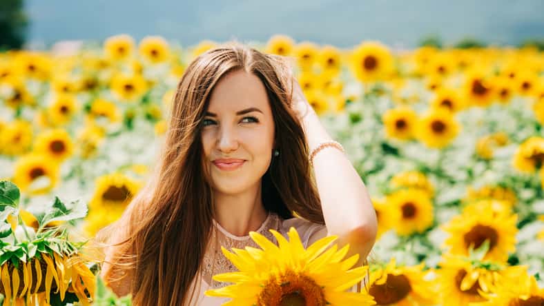 Retrato al aire libre de hermosa mujer joven con girasoles, salud y estilo de vida