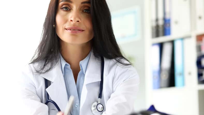 Female GP sitting at worktable in office looking in camera portrait