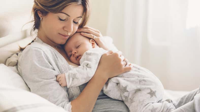 Amar a mamá cariñando de su bebé recién nacido en casa. Retrato brillante de feliz madre sosteniendo un niño infantil dormido en las manos. Madre abrazando a su pequeño hijo de 2 meses.