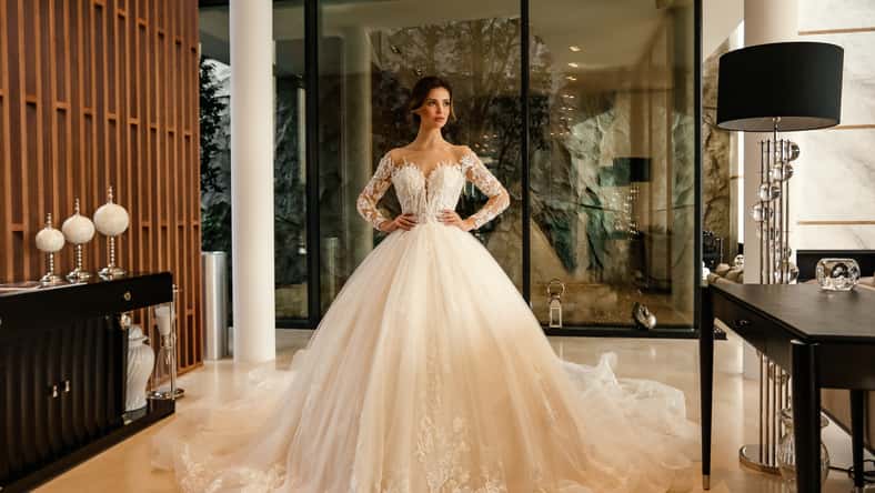 fashion interior photo of beautiful bride with dark hair in elegant wedding dress posing in luxurious interior