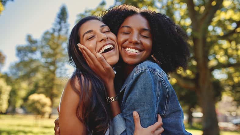 Diverse smiling female friends hugging each other in the park laughing and having fun