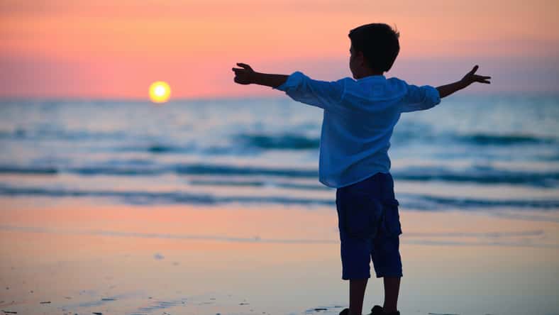 Little boy silhouette on beach at sunset